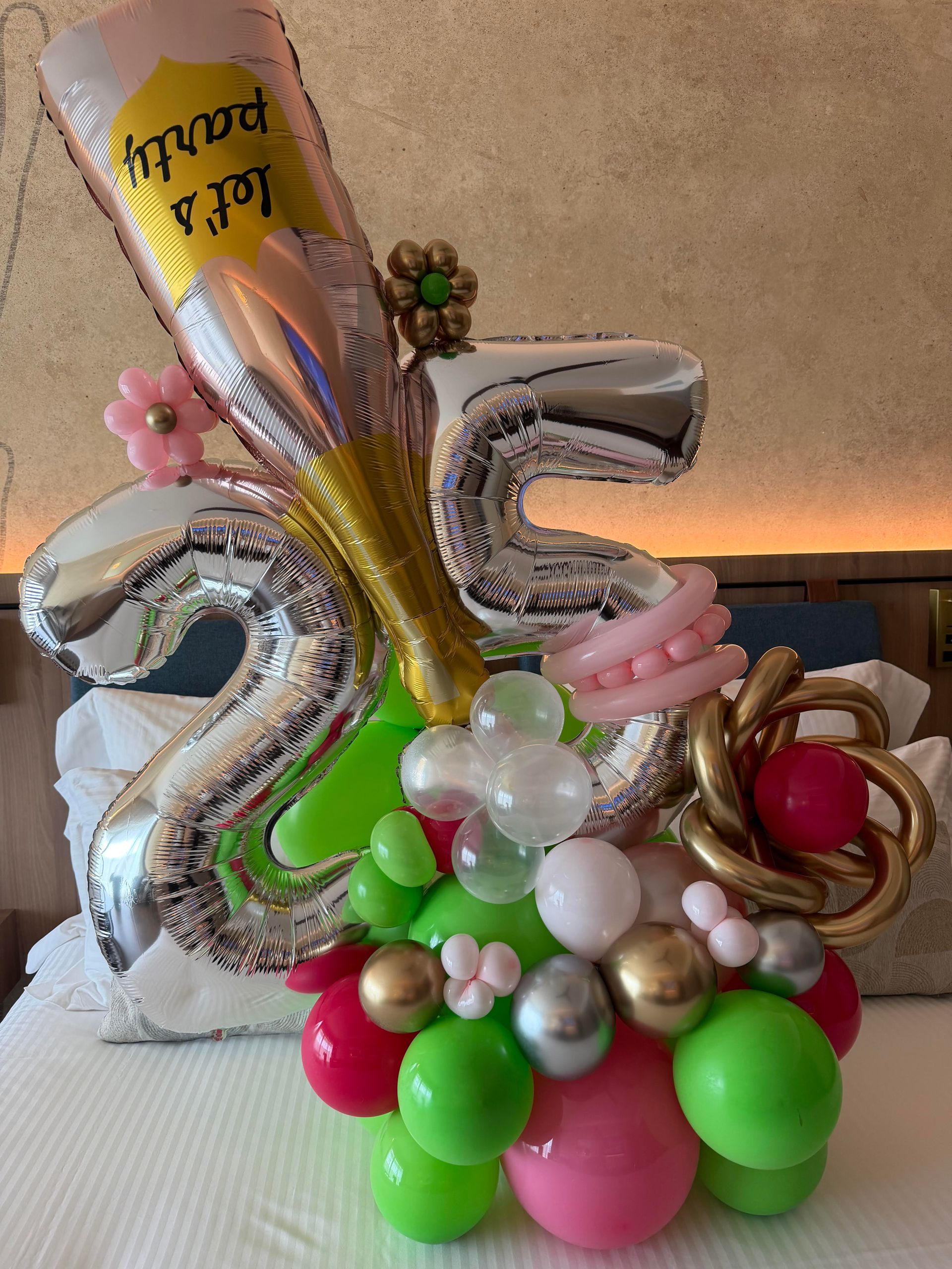 25th birthday balloon bouquet with silver numbers, gold champagne bottle, and pink, green, and white balloons