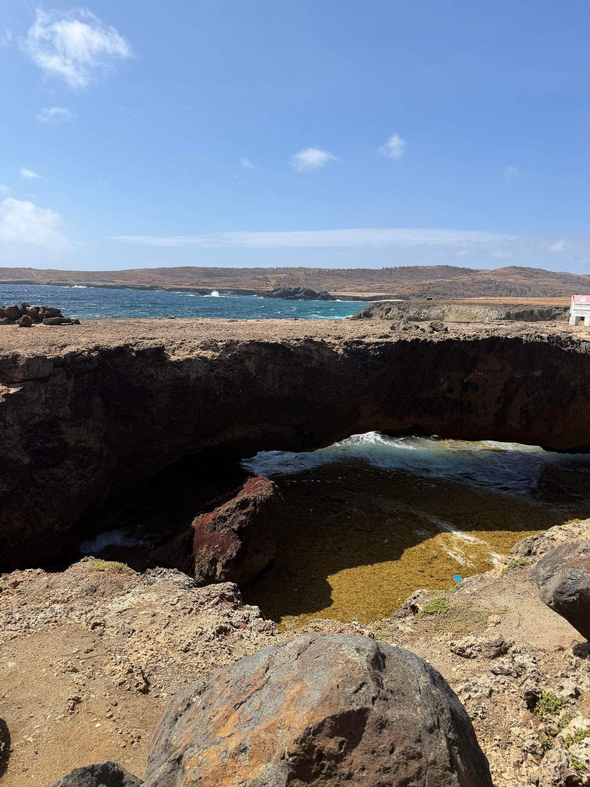 Rocky coastal cave opening with blue sea and sky in the background