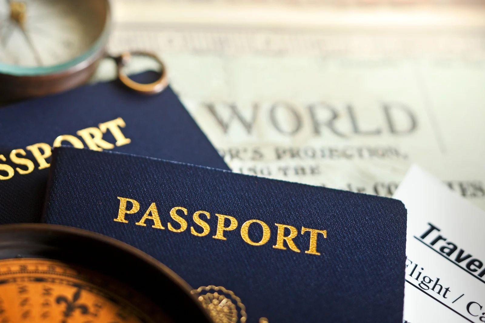 Two navy passports on travel documents with a globe and magnifying glass.