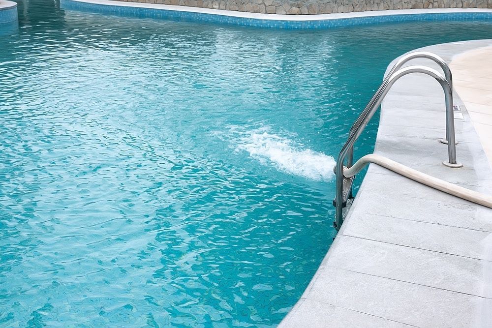 Swimming Pool With Blue Water; Water Jets Out From the Side Near a Metal Ladder — Dean Thomas Pools in Mission Beach, QLD