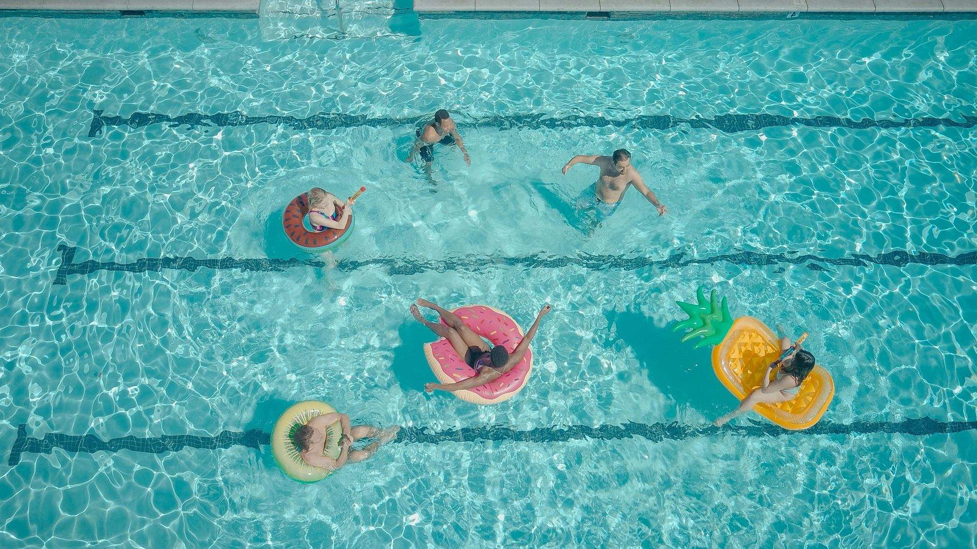 A Pool Net Scoops Debris From a Tiled Pool With Blue and Green Squares — Dean Thomas Pools in Manunda, QLD