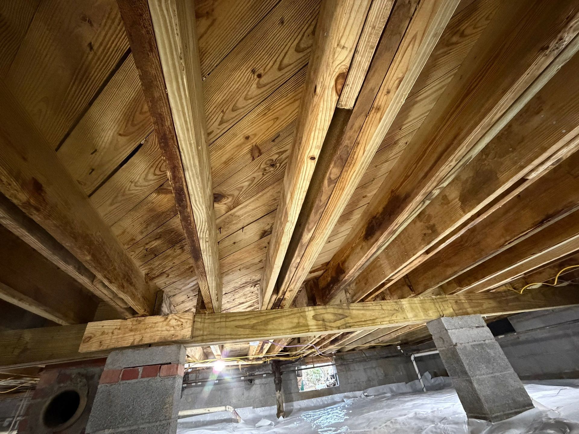 Wooden roof trusses and beams inside an unfinished basement ceiling
