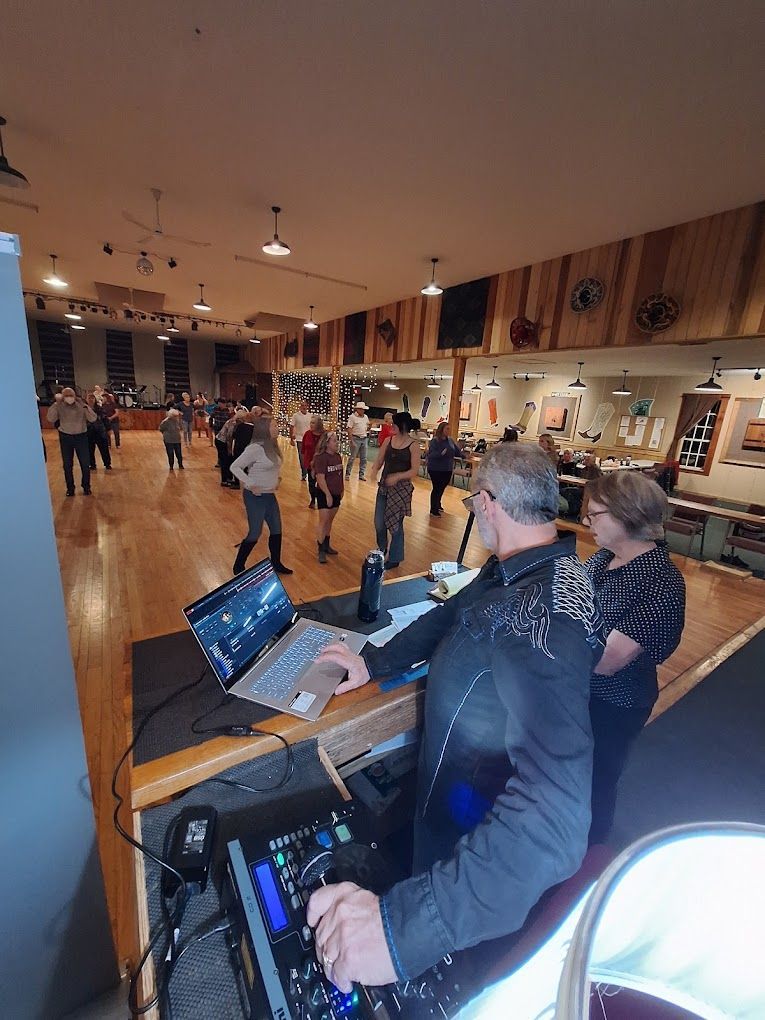 DJ mixing music at a wooden bar venue with people dancing in the background