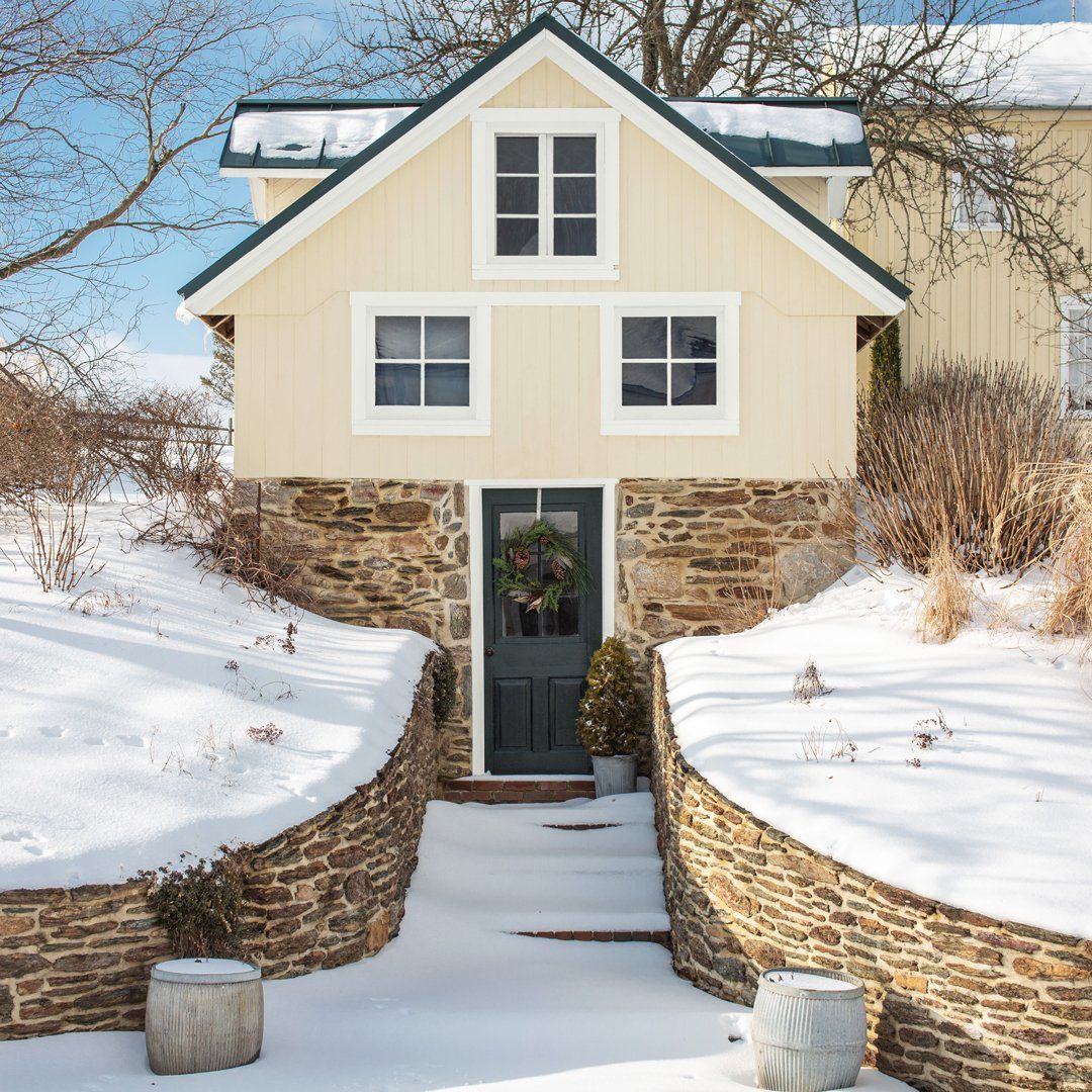 A house with a wreath on the door is surrounded by snow