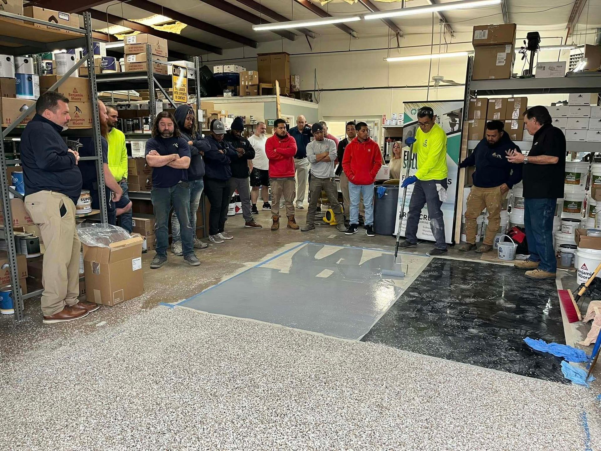 A group of men are standing in a warehouse talking to each other.