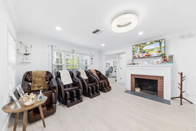 Bright living room with brown recliners, white walls, fireplace, and wall-mounted TV