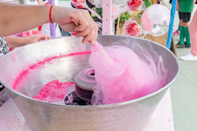 Person spinning pink cotton candy at an outdoor fair booth