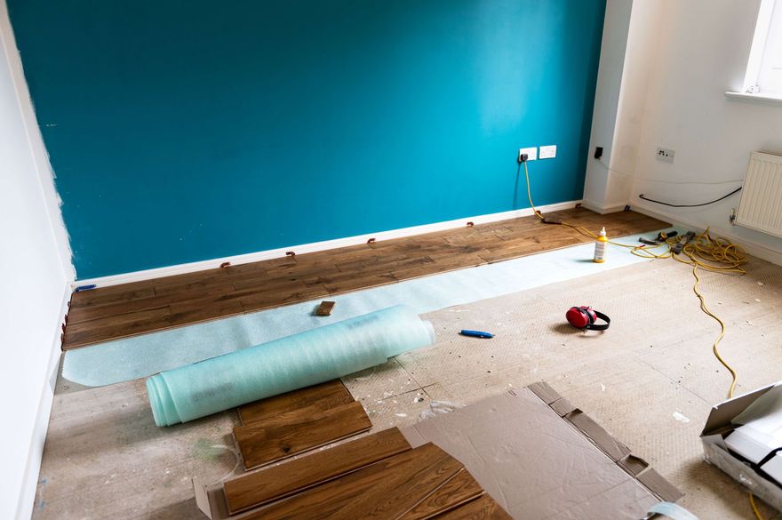 MOST POPULAR Partially renovated room with teal accent wall, wood flooring, scattered tools, and insulation roll on the floor