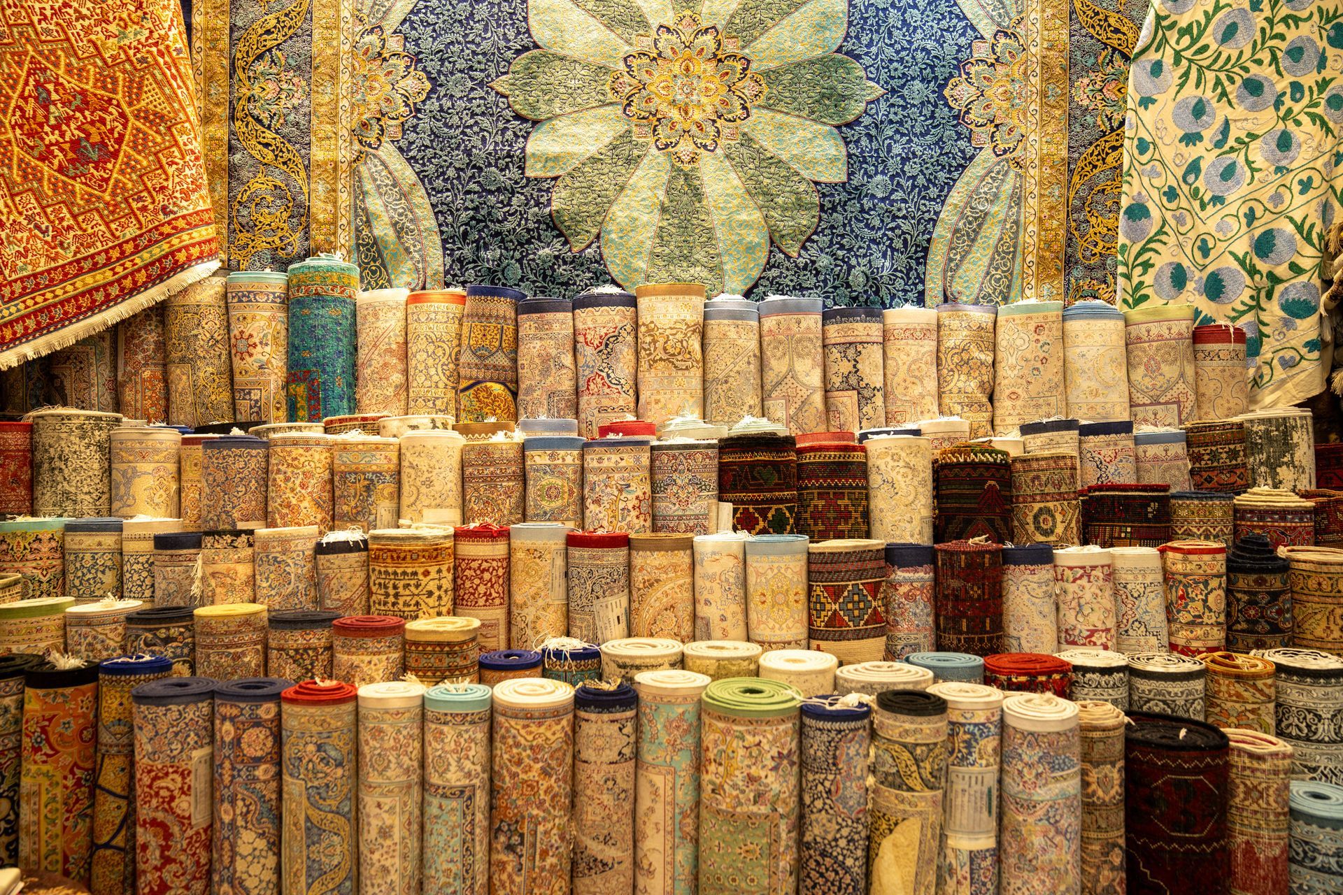 Rows of colorful patterned ceramic cups displayed against ornate mosaic tilework.