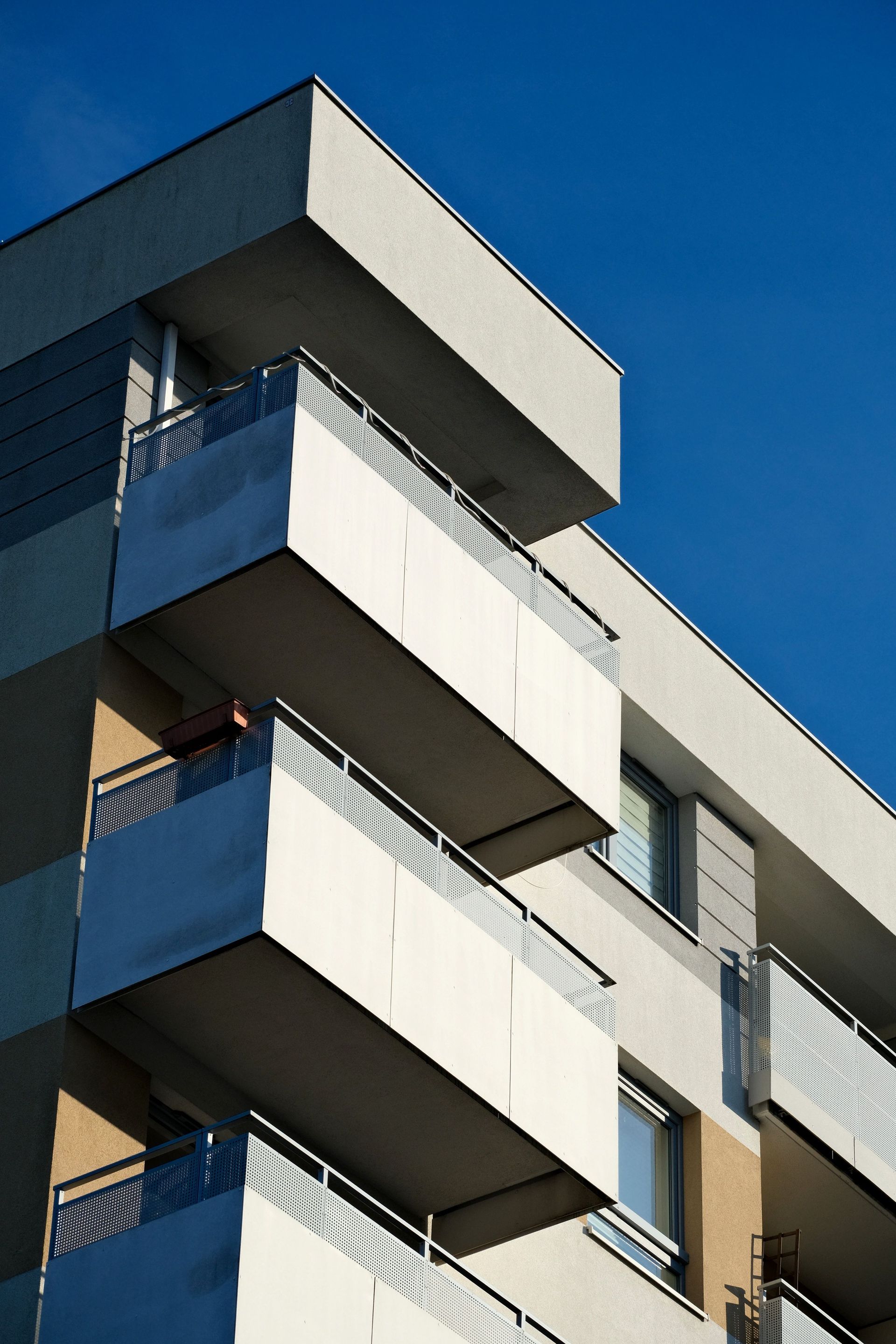 Modern apartment building with white balconies against a clear blue sky