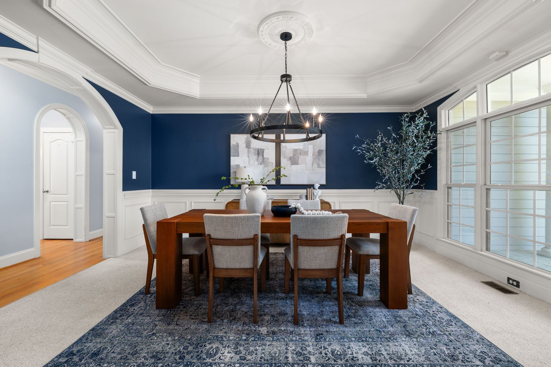 Elegant dining room with dark wood table, blue walls, white trim, and large windows.