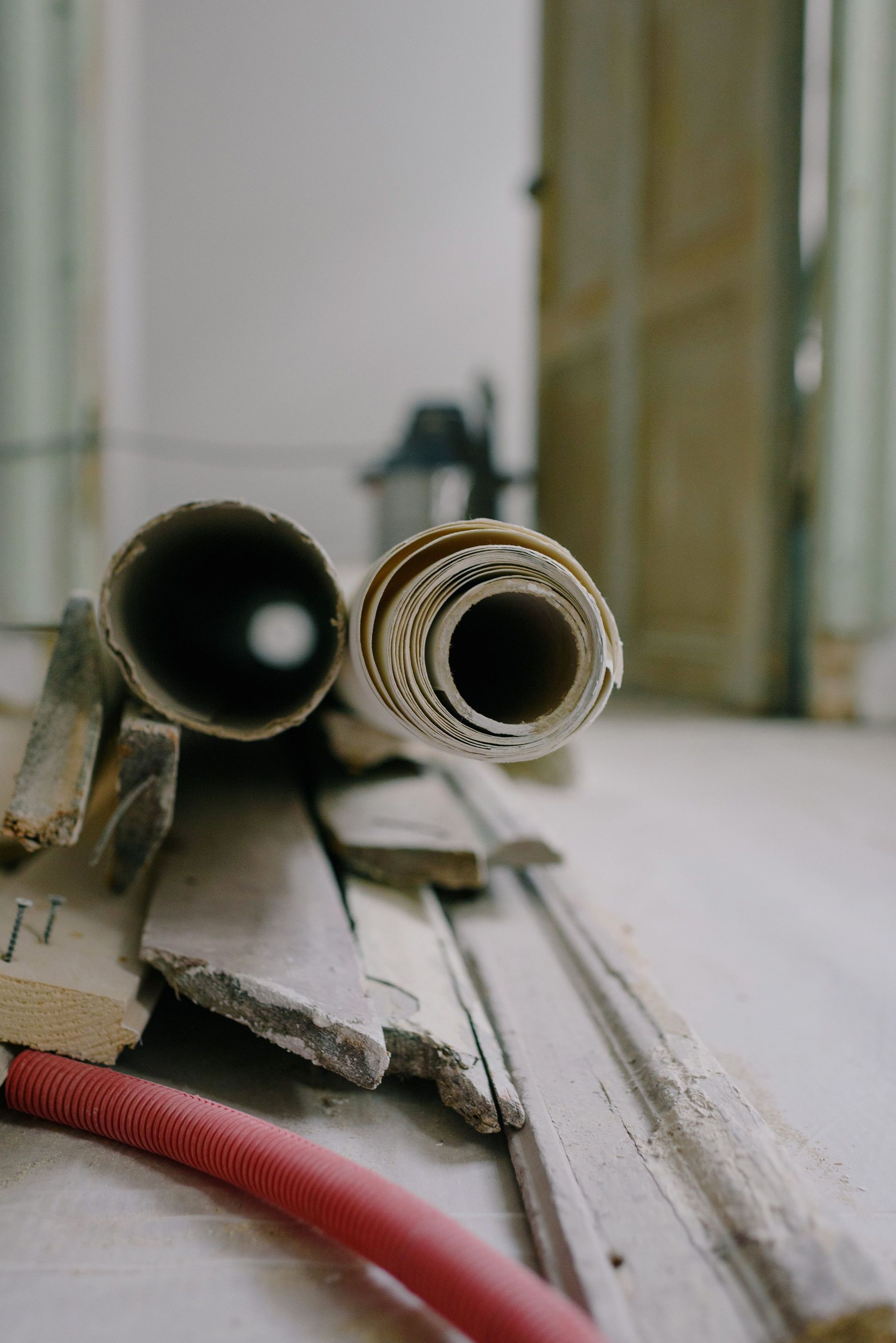 Coiled red hose and rolled material on a dusty windowsill, with a blurred room in the background