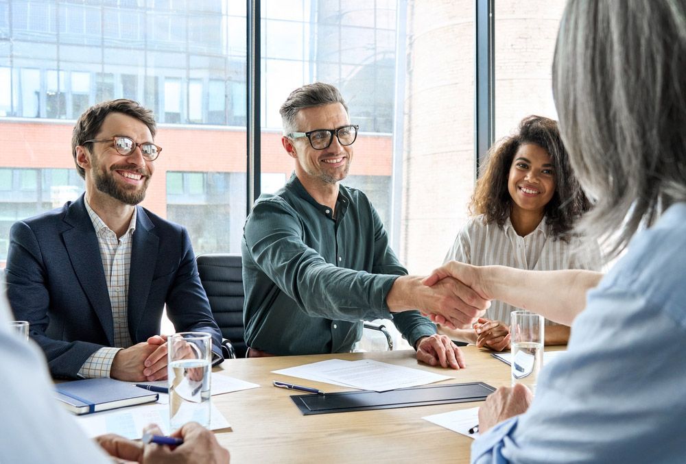 A Group of People Sit Around a Table, Engaging in Handshakes — Workplace Conflict Resolution in Kingscliff, NSW