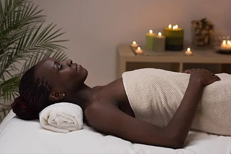 A woman is laying on a massage table wrapped in a towel.