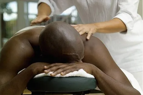 A man is laying on a table getting a massage from a woman.