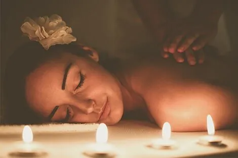 A woman is getting a massage in a spa surrounded by candles.