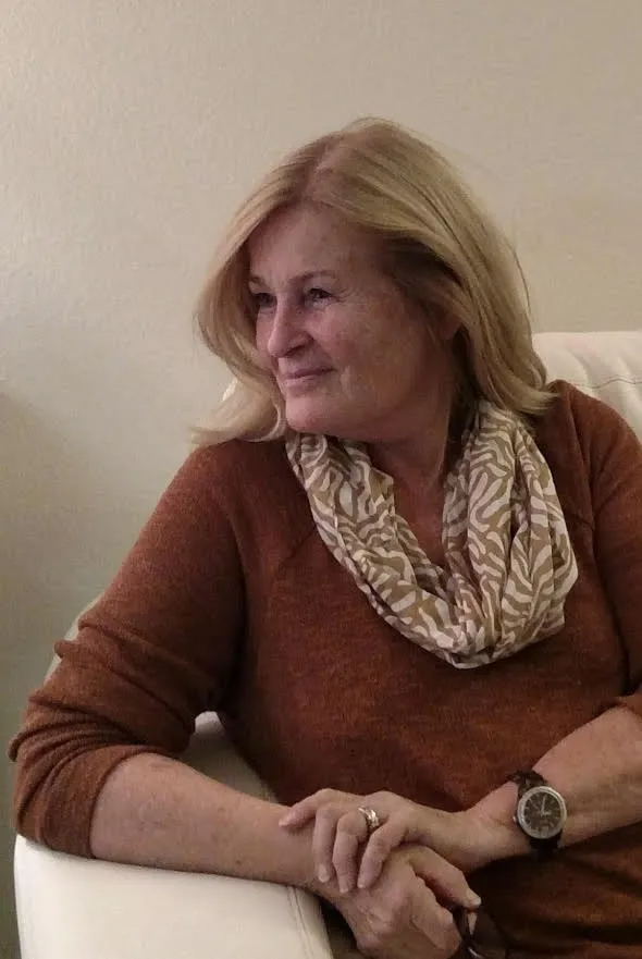 A woman is sitting in a chair wearing a scarf and a watch.