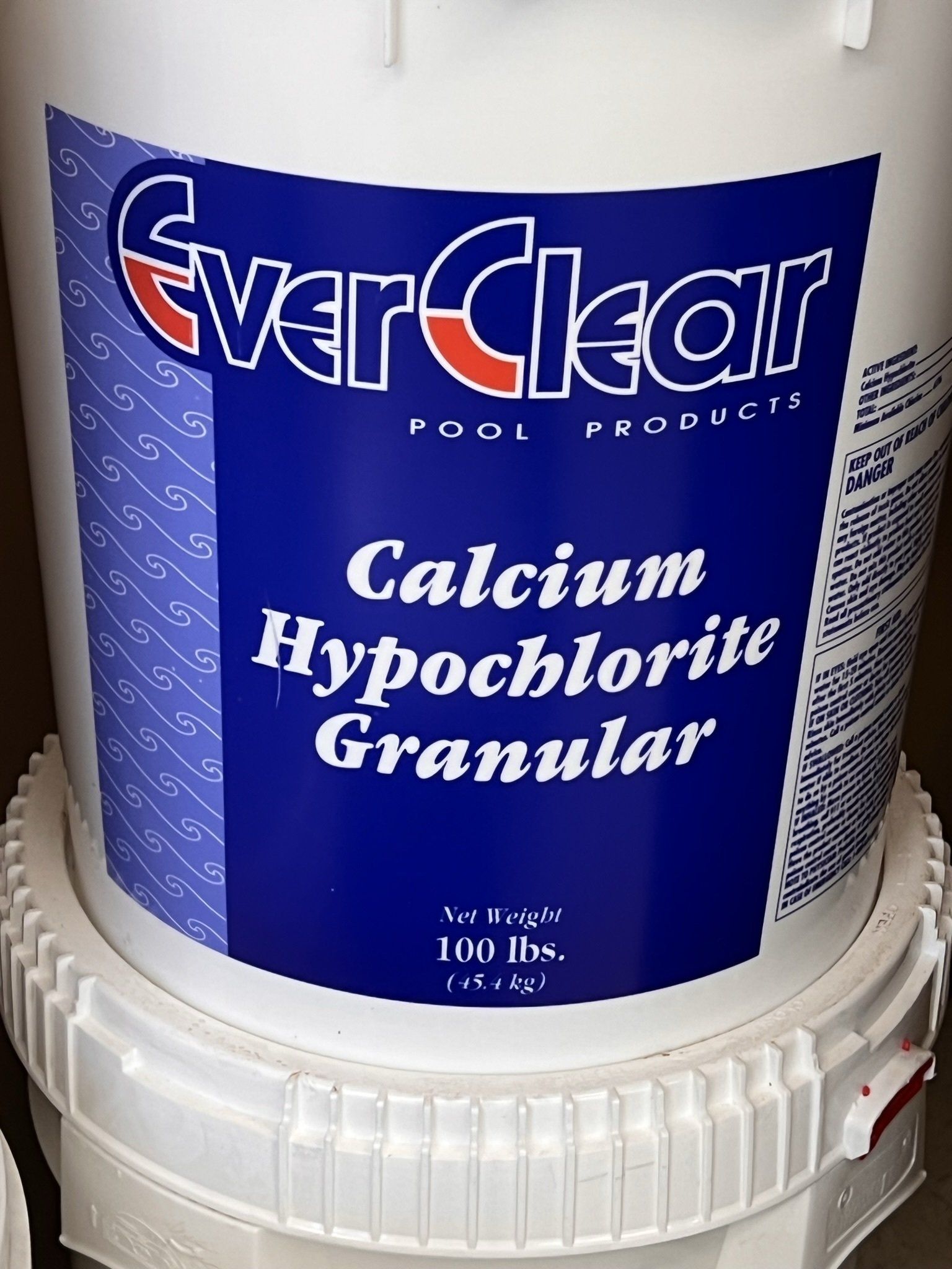 White bucket of EverClear pool products, Calcium Hypochlorite Granular, 100 lbs. label, blue and white.