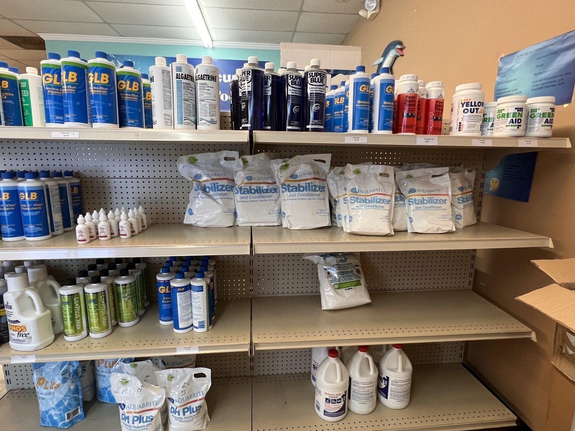 Shelves stocked with pool chemicals in a store. Blue, white, and red containers are visible.