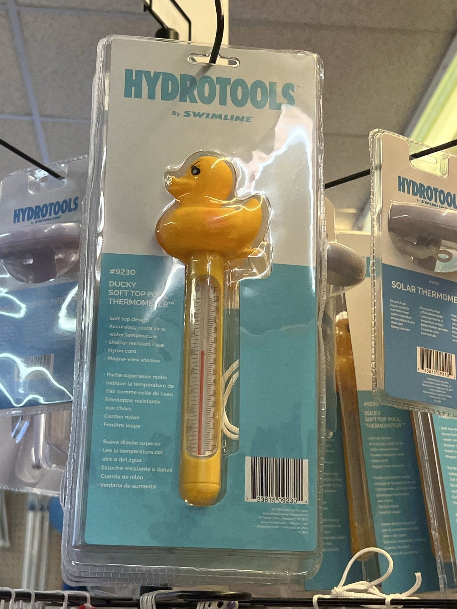 Yellow rubber duck pool thermometer in a package, hanging in a store.