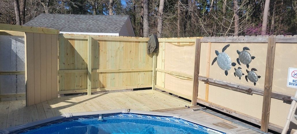 Wooden fence with turtle decorations surrounding a pool deck.