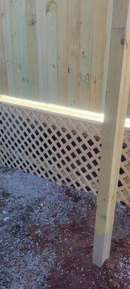 Wooden fence with lattice bottom section and gravel ground.