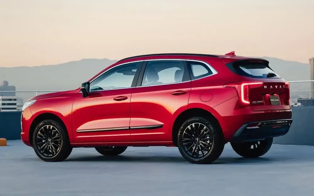 Un SUV rojo estacionado en una azotea al atardecer con montañas al fondo.