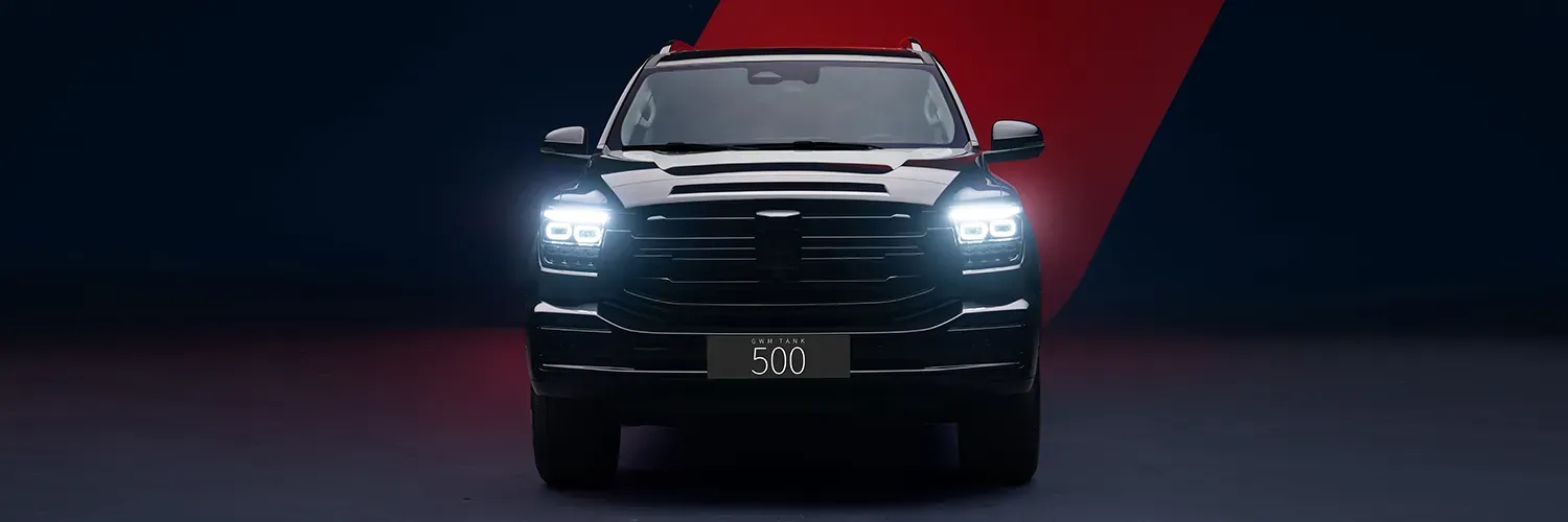 Vista frontal de un SUV negro con faros brillantes sobre un fondo de estudio rojo oscuro y negro.