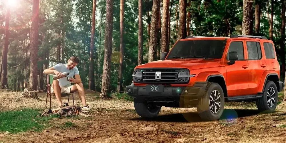 Un SUV naranja estacionado en un bosque junto a una persona sentada en una silla plegable junto a una fogata.
