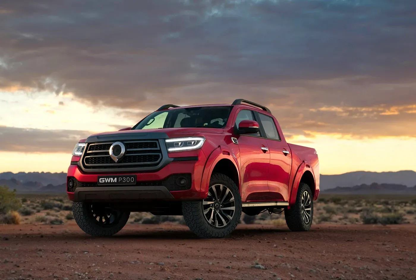 Camioneta roja estacionada en un camino de tierra al atardecer con montañas al fondo.