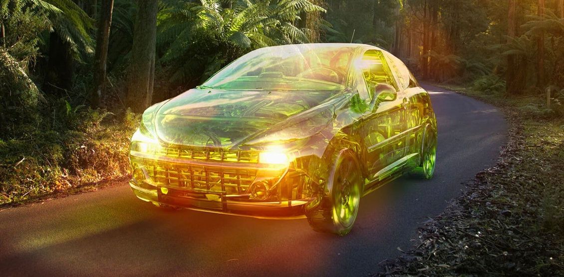 Un coche color oro circula por una sinuosa carretera forestal al atardecer.