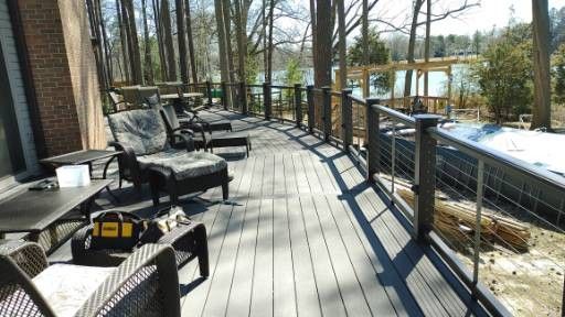 A partially built wood deck attached to a gray house, featuring white railings and a view of trees in the background. A partially built wood deck attached to a gray house, featuring white railings and a view of trees in the background.