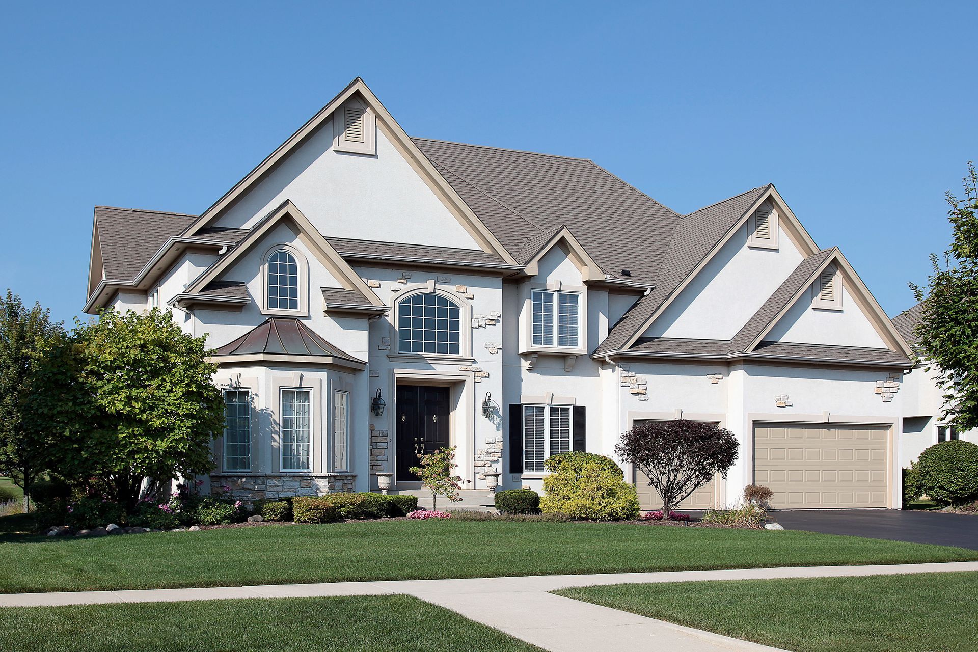 A large two-story white suburban house with a brown shingled roof, a front lawn, and an attached two-car garage. A large two-story white suburban house with a brown shingled roof, a front lawn, and an attached two-car garage.
