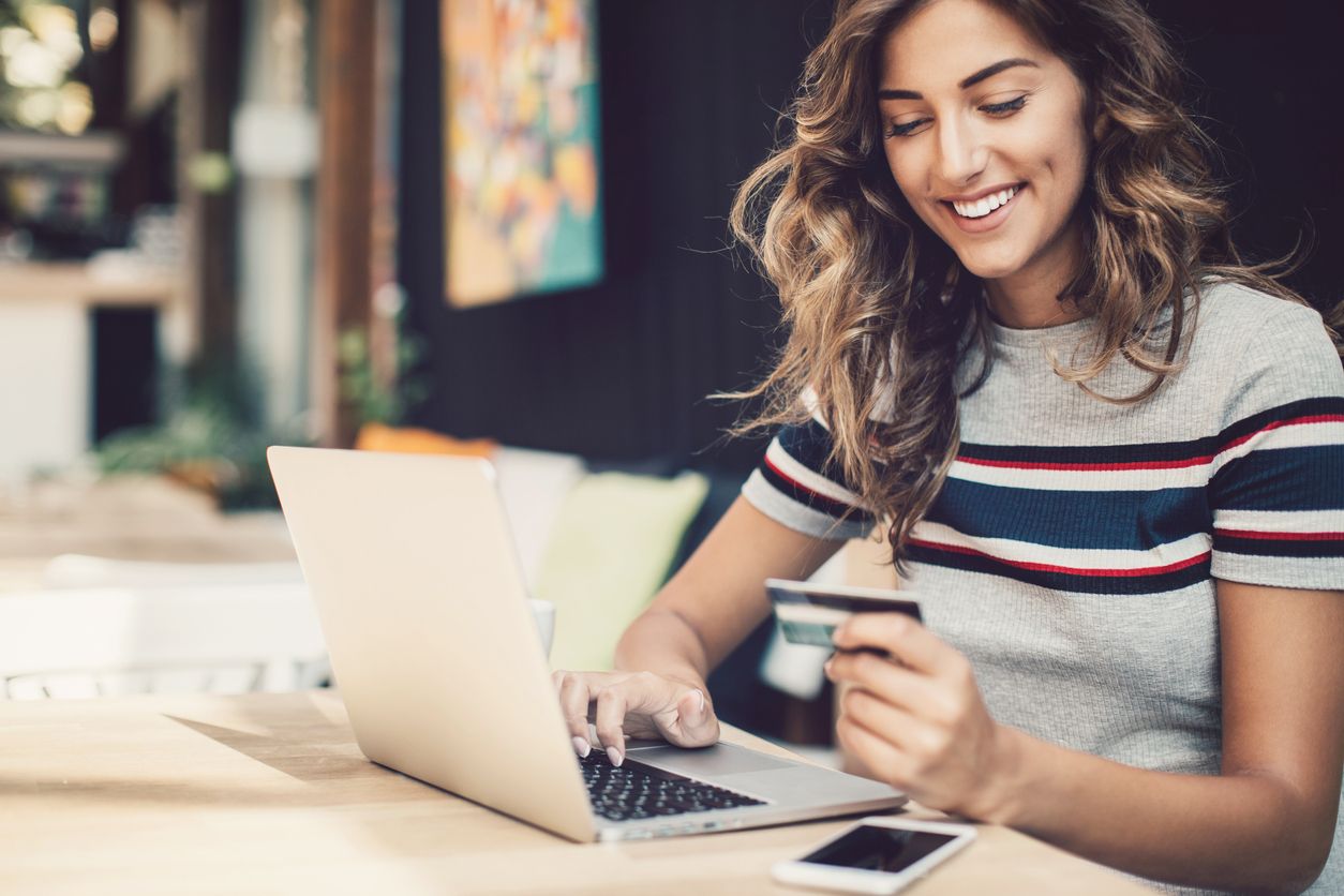a woman is holding a credit card while using a laptop computer .