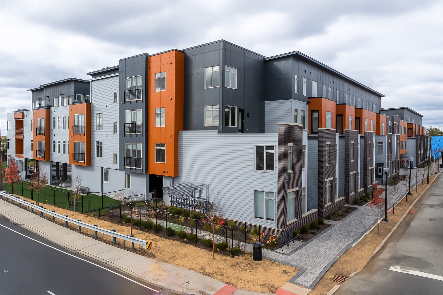 Modern multi-unit apartment building with gray, orange, and wood-toned siding, on a corner lot.
