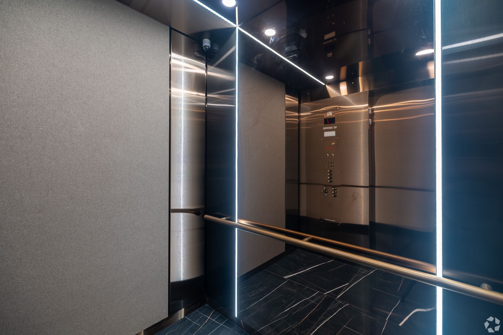 Modern elevator interior with stainless steel walls, black and white floor, and LED lighting.