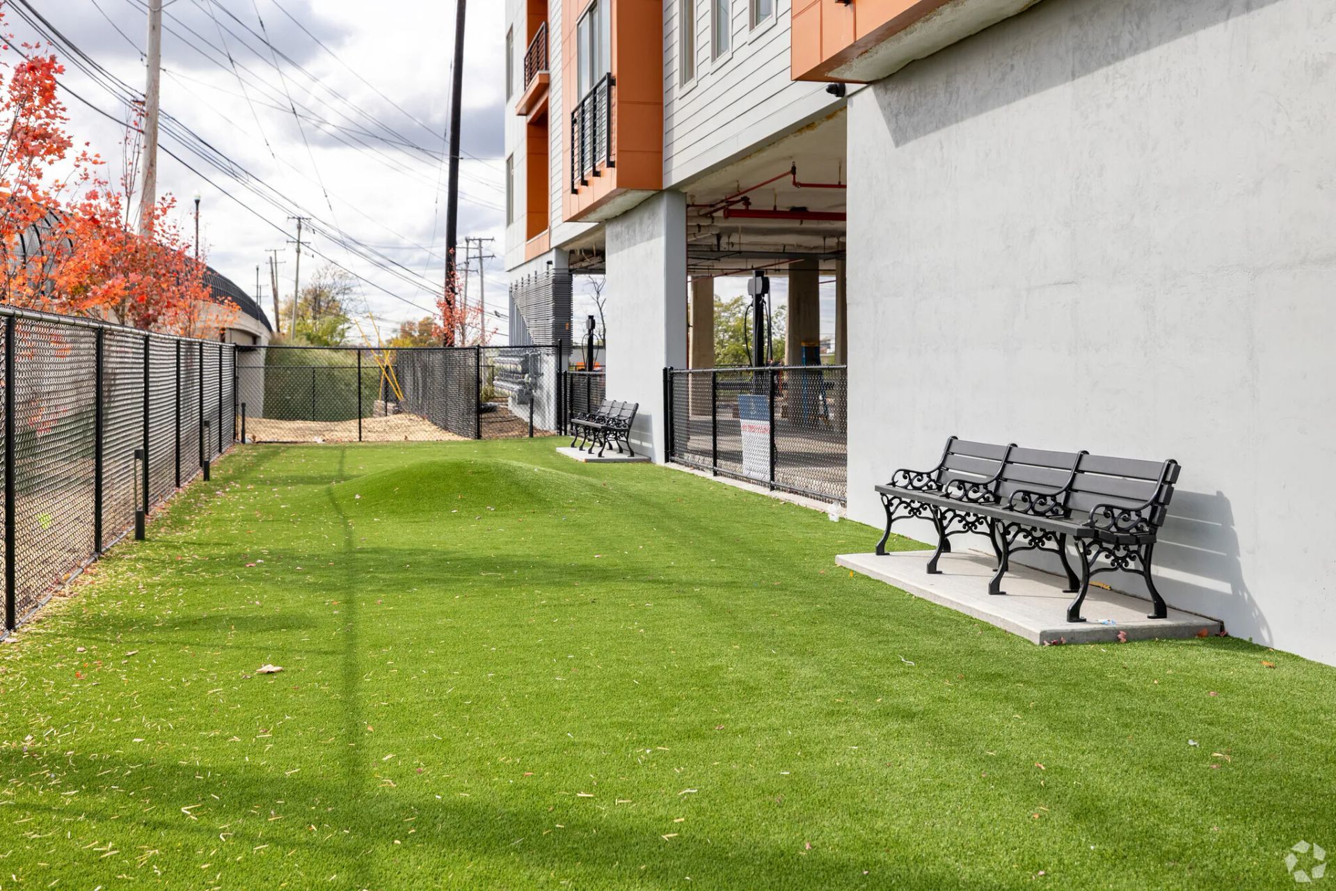 Artificial turf dog park with a bench next to a building.