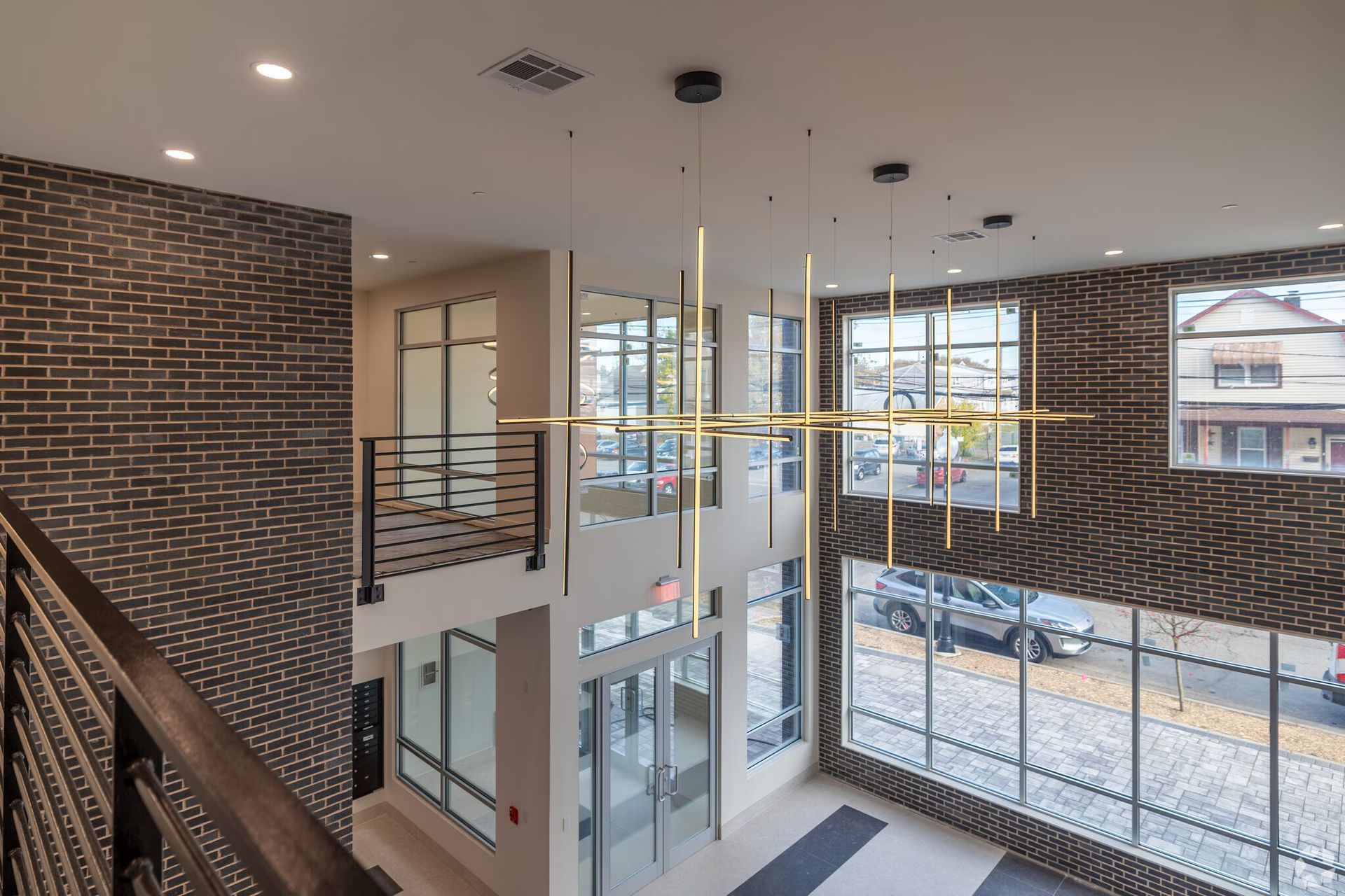 Interior view of a modern building lobby with brick walls, large windows, and a multi-light fixture.