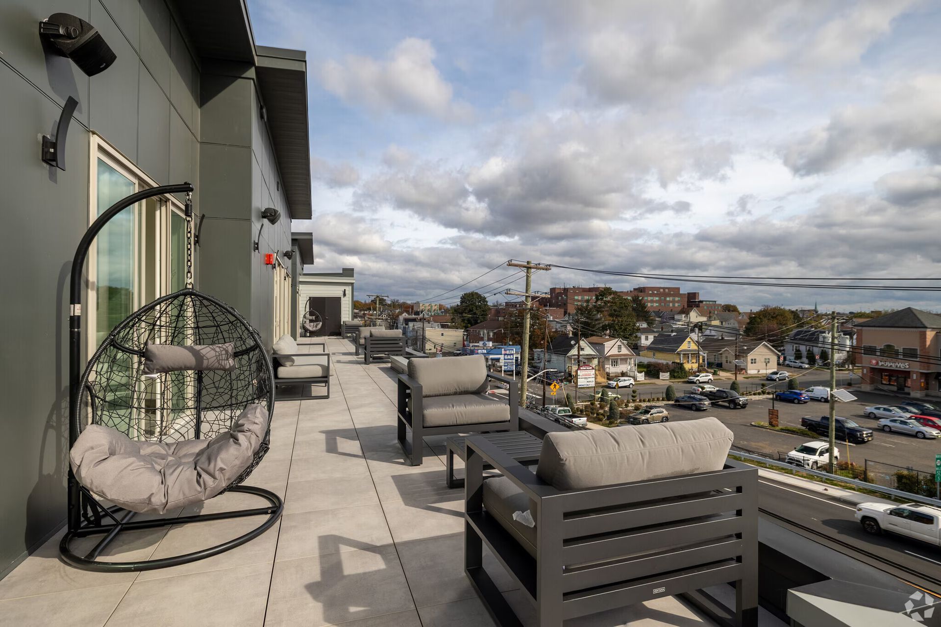 Outdoor patio with seating overlooking a city and water on an overcast day.