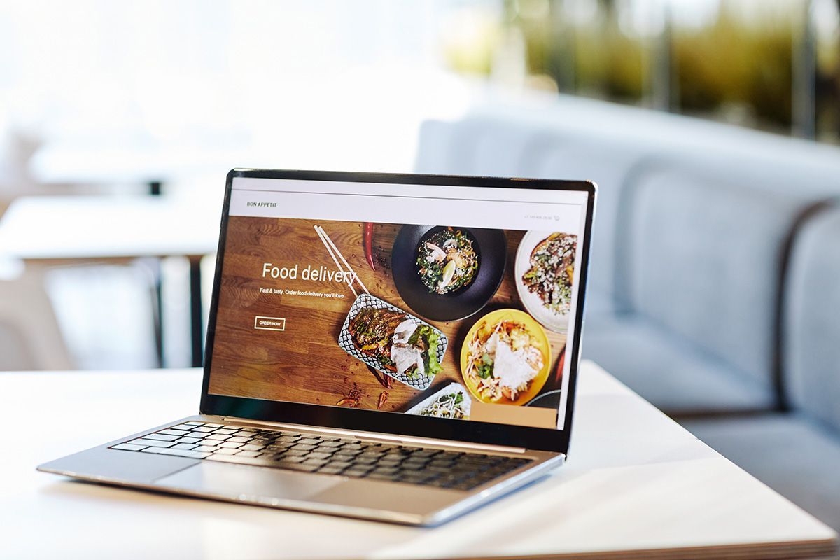 Laptop displaying a food delivery ecommerce website with product photos and an order button