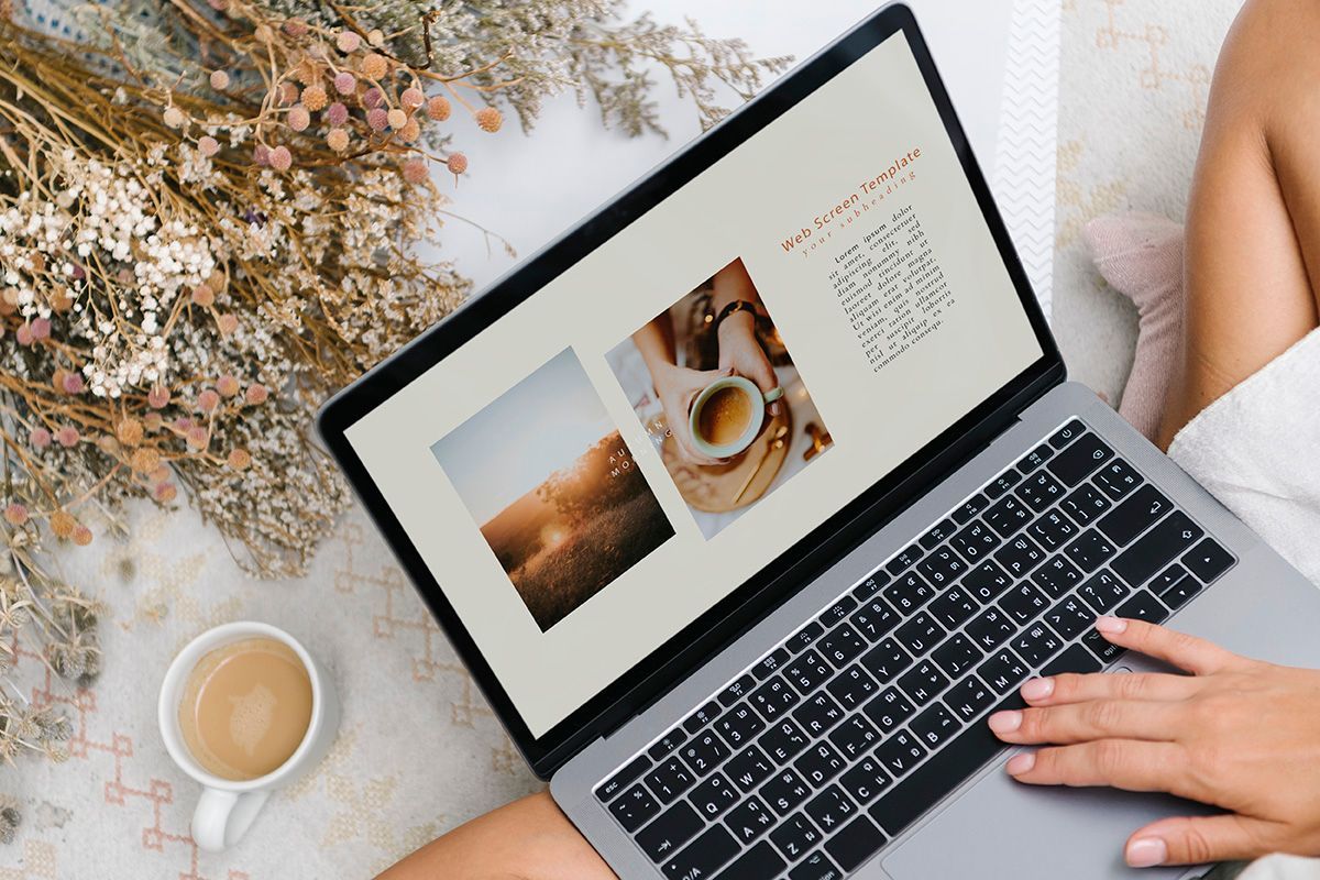 Person browsing a custom web design template on a laptop surrounded by dried flowers and a coffee cup