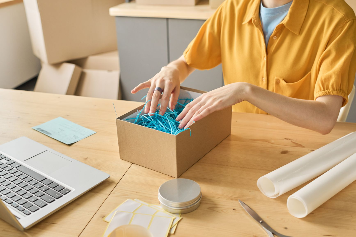 The real faces behind the brand Hands packing a cardboard box for a small business order