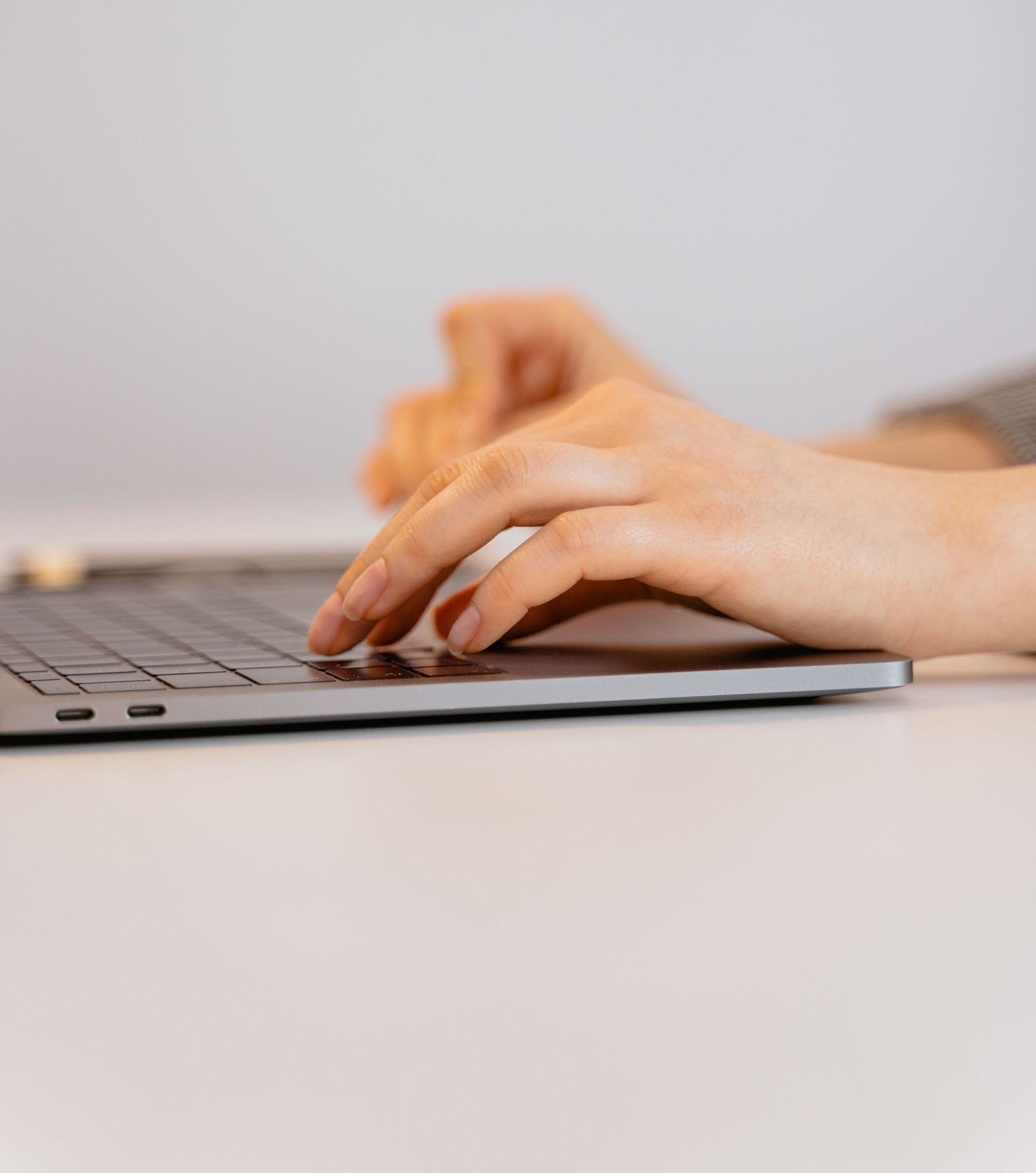 Hands typing on a laptop keyboard at a desk