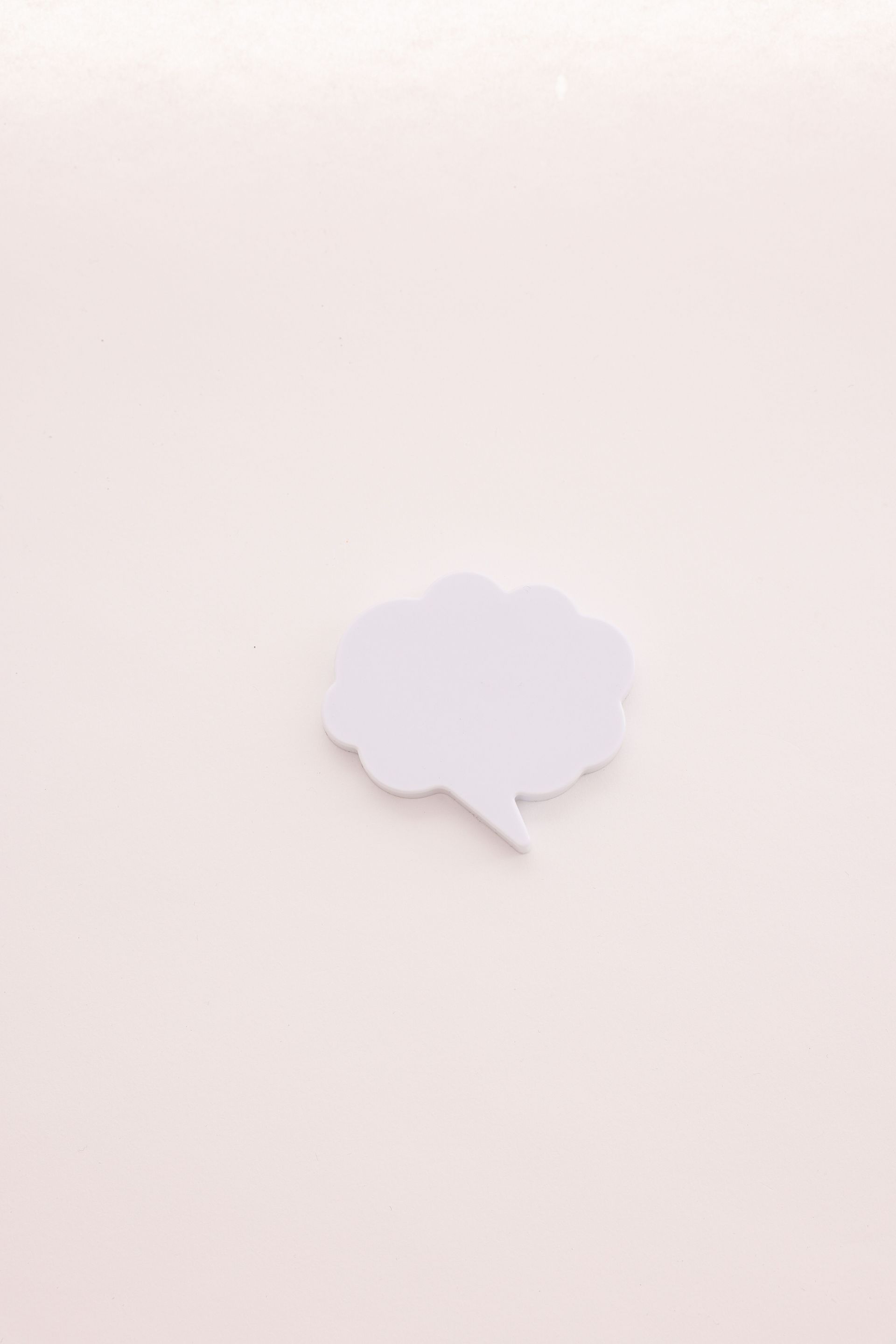 Small white speech bubble cutout on a pale pink background.
