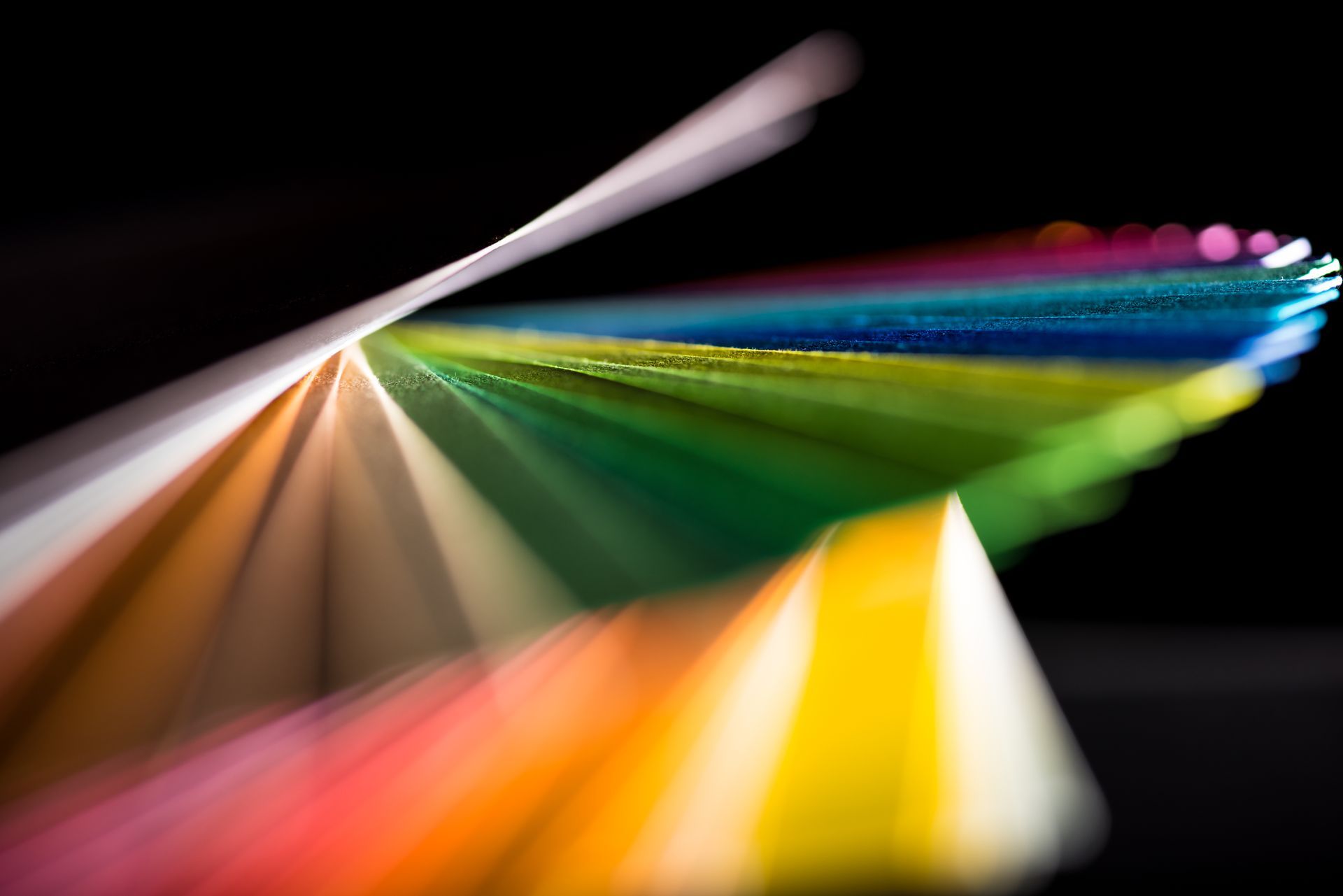 Rainbow colored paper swatches fanned out against a black background