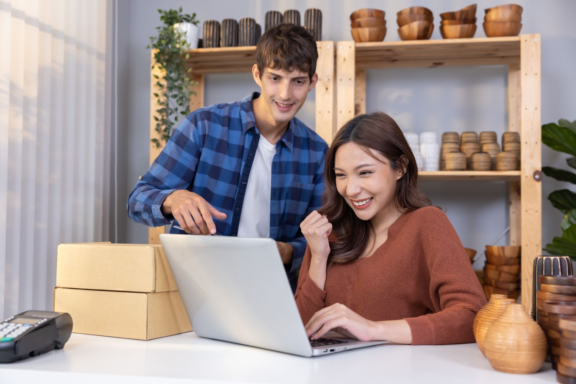 Two small business owners smiling and working together on their Shopify store 