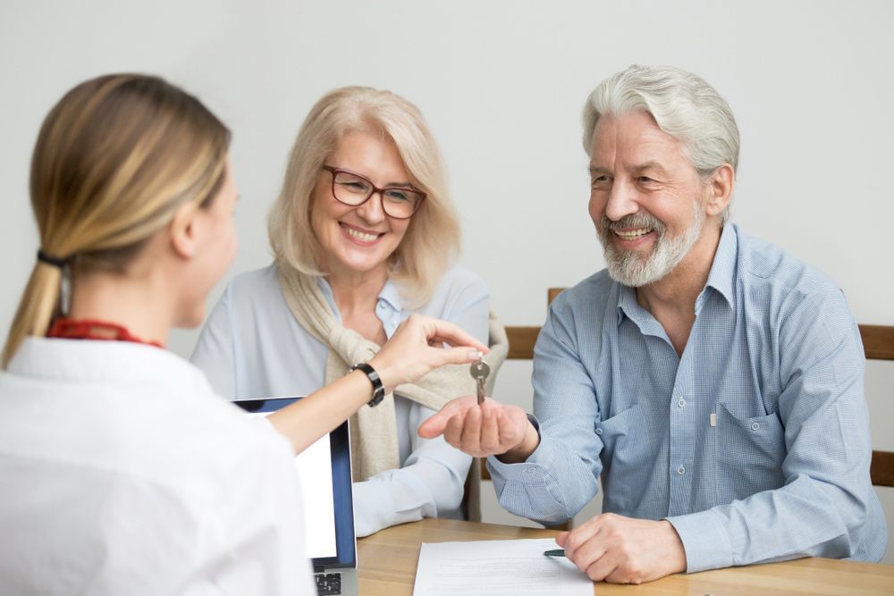 A Woman Is Giving a Man and Woman a Set of Keys — A M Conveyancing Pty Ltd In Northern Rivers, NSW