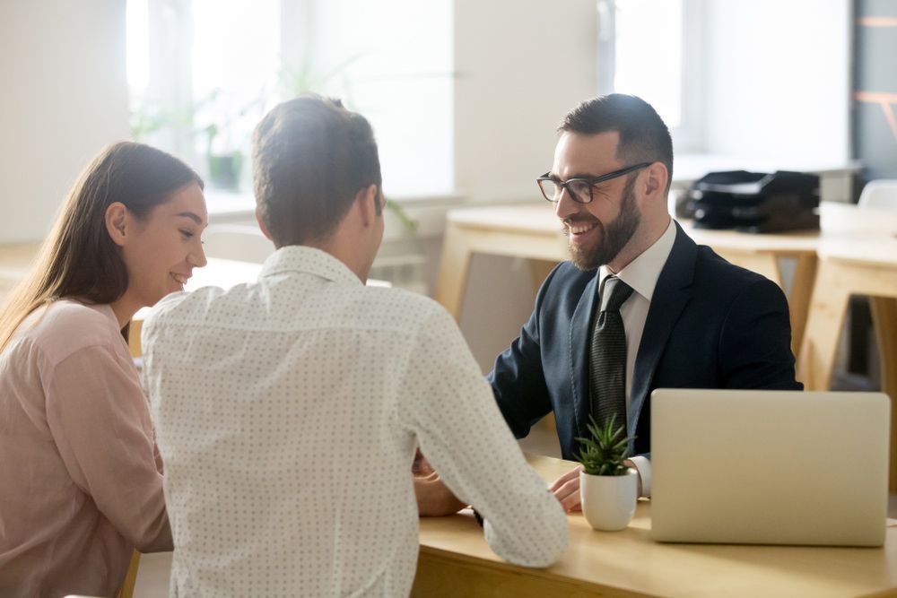 A Man and A Woman Are Sitting at A Table Talking to A Man in A Suit — A M Conveyancing Pty Ltd In Gold Coast, QLD
