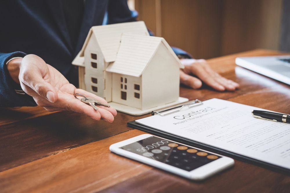 A Person Is Holding a Model House and Keys in Their Hand — A M Conveyancing Pty Ltd In Gold Coast, QLD