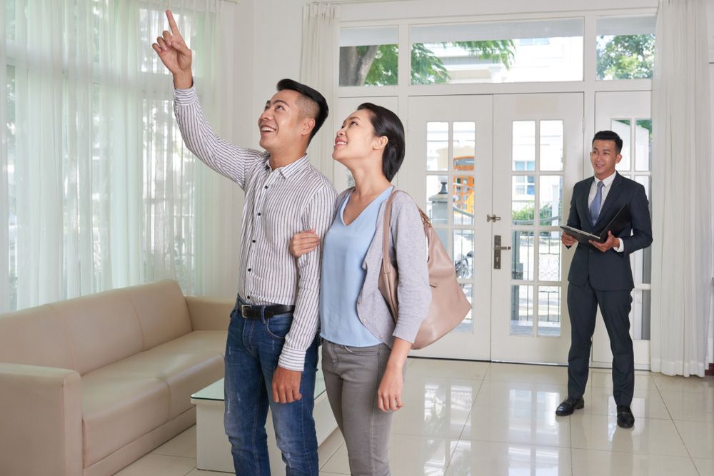 A Man and Woman Are Looking at A House with A Real Estate Agent — A M Conveyancing Pty Ltd In Gold Coast, QLD